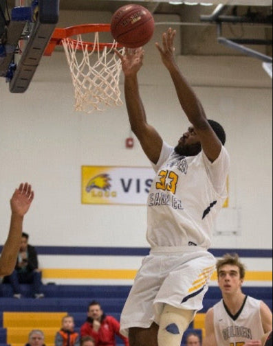 Basketball player dunking the ball during a game in a gymnasium.